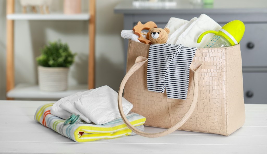 Mom's bag with feeding bottle and baby clothes